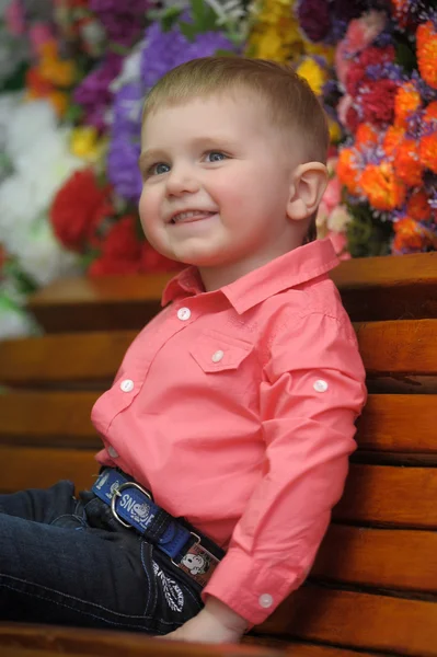 Niño cerca de los bancos con flores en el fondo — Foto de Stock