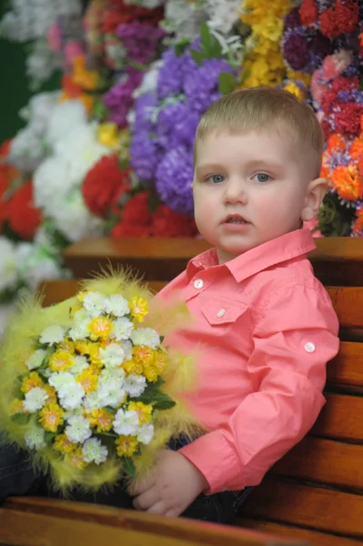 Enfant près des bancs avec des fleurs sur le fond — Photo