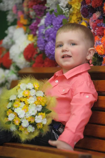 Enfant près des bancs avec des fleurs sur le fond — Photo
