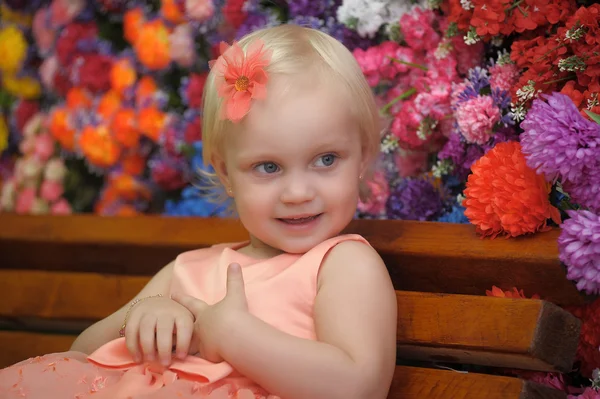 Dziecko w pobliżu ławki z kwiatami na tle — Zdjęcie stockowe