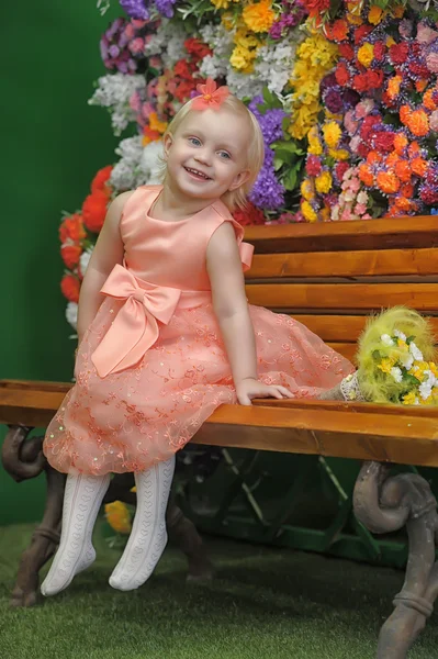 Dziecko w pobliżu ławki z kwiatami na tle — Zdjęcie stockowe