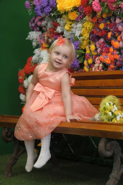 Child near the benches with flowers on the background — Stock Photo, Image