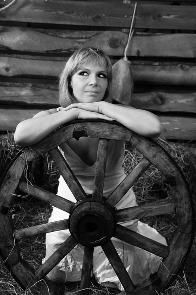 Vintage portrait of a beautiful woman with a wooden wheel on a farm — Stock Photo, Image