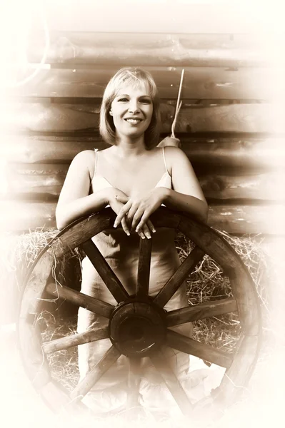 Vintage portrait of a beautiful woman with a wooden wheel on a farm — Stock Photo, Image