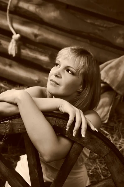 Retrato de una hermosa mujer con una rueda de madera en una granja — Foto de Stock