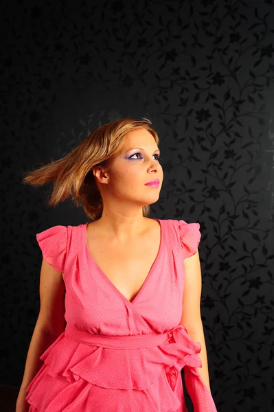 Portret van een mooie vrouw in een roze jurk op een zwarte achtergrond — Stockfoto