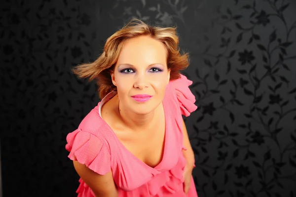 Portrait of a beautiful woman in a pink dress on a black background — Stock Photo, Image