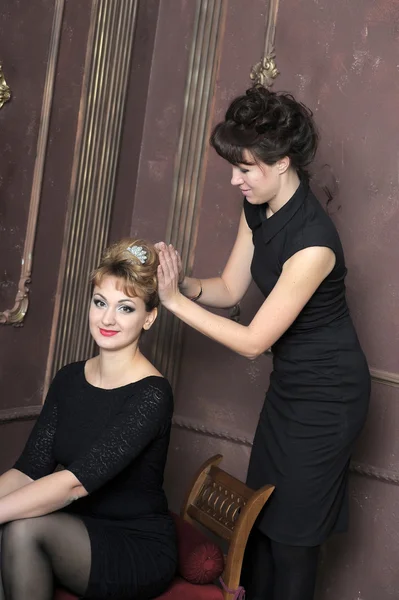 Парикмахер делает прическу для молодых красивых женщин — стоковое фото