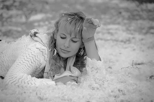 Beautiful woman lying in the feathers — Stock Photo, Image