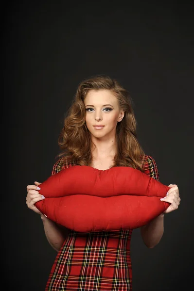 Beautiful girl holding a pillow in the shape of lips — Stock Photo, Image