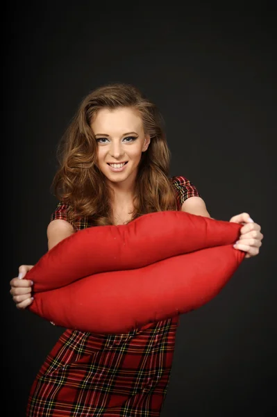 Beautiful girl holding a pillow in the shape of lips — Stock Photo, Image