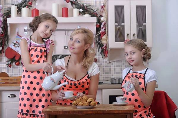 Mamma med hennes döttrar i köket dricka te med cupcakes — Stockfoto