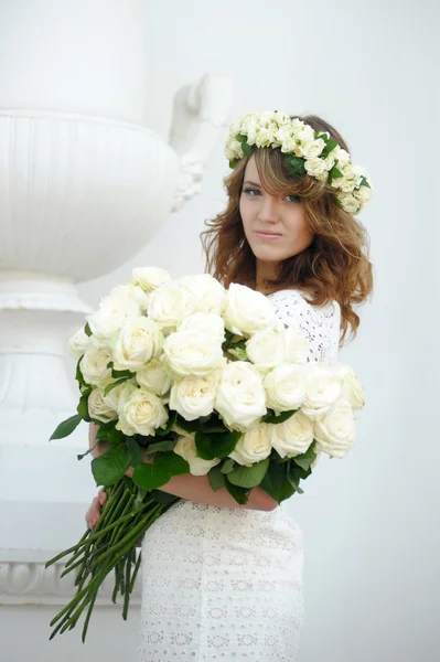 Porträt einer schönen Frau mit einem Strauß weißer Rosen und einem Kranz auf dem Kopf — Stockfoto