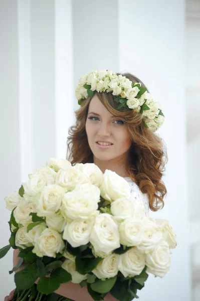 Porträt einer schönen Frau mit einem Strauß weißer Rosen und einem Kranz auf dem Kopf — Stockfoto