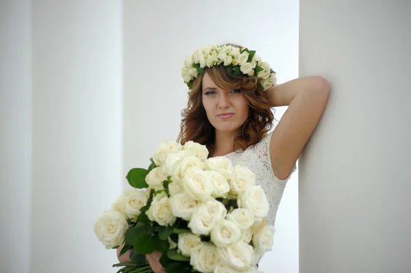 Porträt einer schönen Frau mit einem Strauß weißer Rosen und einem Kranz auf dem Kopf — Stockfoto