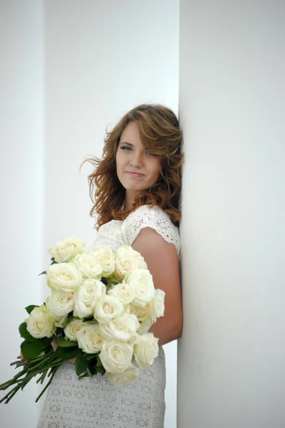 Retrato de una hermosa mujer con un ramo de rosas blancas y una corona en la cabeza — Foto de Stock