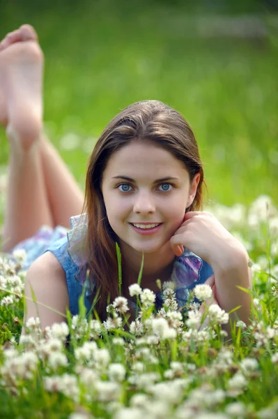 Sorrindo menina pré-adolescente deitada no fundo trevo verde — Fotografia de Stock