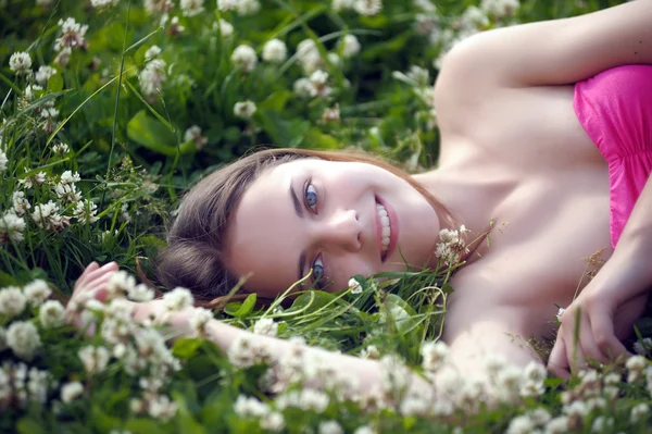 Sorrindo menina pré-adolescente deitada no fundo trevo verde — Fotografia de Stock