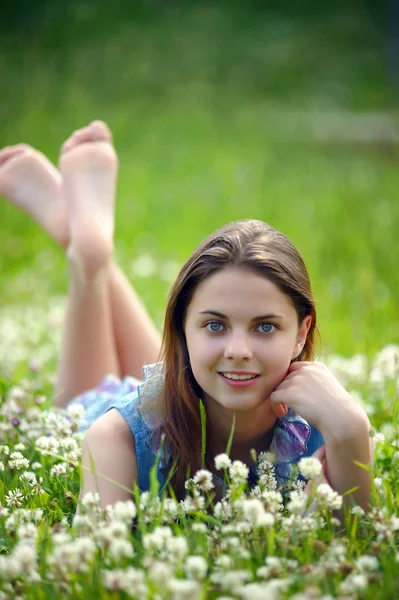 Sorrindo menina pré-adolescente deitada no fundo trevo verde — Fotografia de Stock