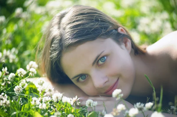 Sorrindo menina pré-adolescente deitada no fundo trevo verde — Fotografia de Stock