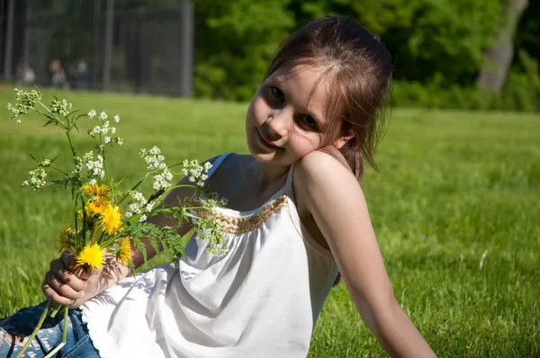 Petite fille sur l'herbe avec des fleurs — Photo