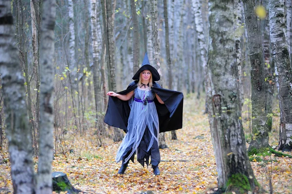 Meisje in een heks kostuum in het bos — Stockfoto