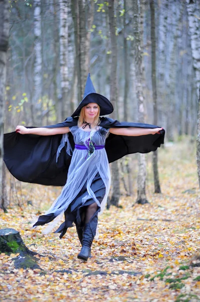 Menina em um traje de bruxa na floresta — Fotografia de Stock