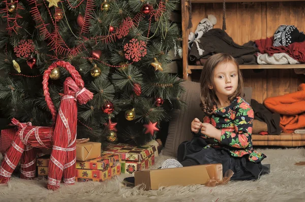 Kleines Mädchen mit Geschenken in der Nähe eines Weihnachtsbaums — Stockfoto