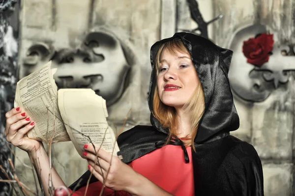 Woman in a red dress and a black cloak with a hood on Halloween — Stock Photo, Image