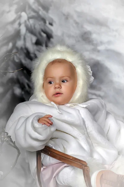 Menina em um trenó ao lado de um boneco de neve . — Fotografia de Stock