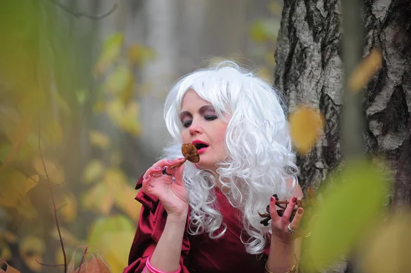 Mooie jonge vrouw in het beeld van de heks in het bos op halloween. — Stockfoto