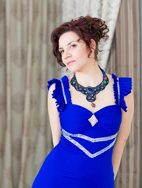 Retrato de mujer elegante en elegante vestido azul y collar elaborado, buscando relajado . — Foto de Stock