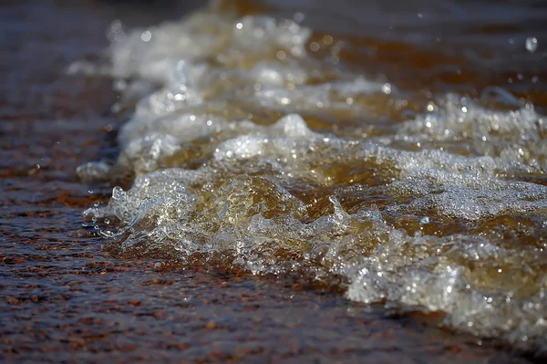 Onda oceânica espumosa em uma praia de areia . — Fotografia de Stock