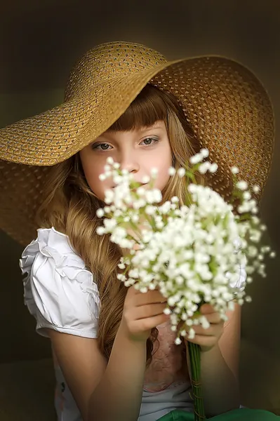 Chica en un sombrero de paja con un ramo de lirios del valle — Foto de Stock