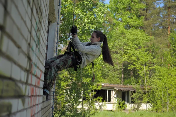 Menina pendura de um edifício no equipamento de escalada — Fotografia de Stock