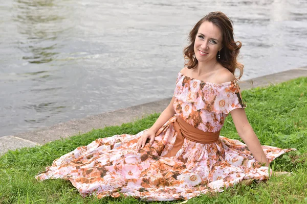 Красива Брюнетка Рожевій Сукні Сидить Траві Біля Річки — стокове фото