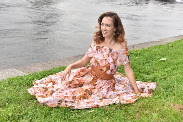 Beautiful Brunette Woman Pink Dress Sits Grass River — Stock Photo, Image