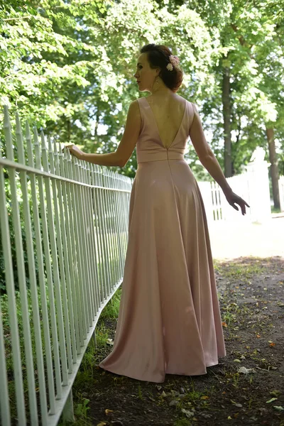 公園のピンクのドレスの美しいエレガントなブルネットの女性 — ストック写真