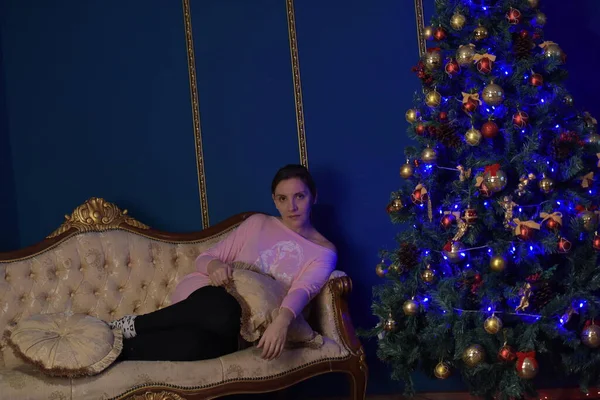 40歳の女性がソファの上の青い色調のクリスマスインテリアで — ストック写真