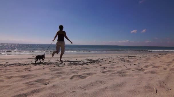 Femme courant avec son chien sur la plage — Video