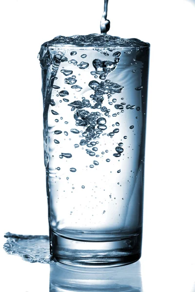 Νερό ρίχνει στο ποτήρι που απομονώνονται σε λευκό φόντο — Φωτογραφία Αρχείου