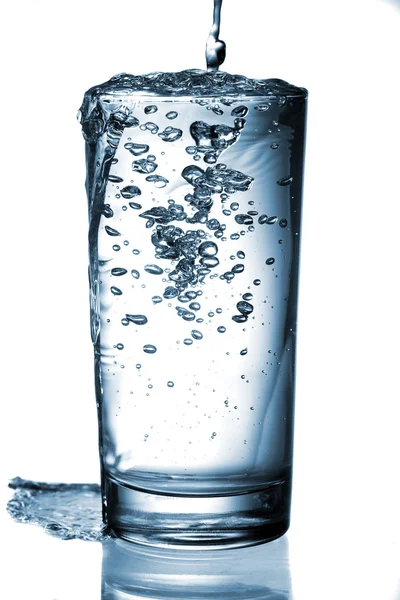 Agua vertiendo en vidrio aislado sobre fondo blanco — Foto de Stock