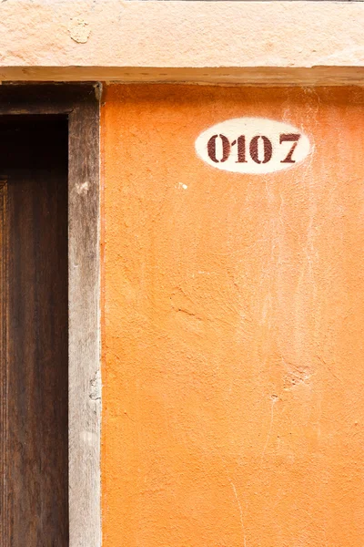 Number 0107 on old brown concrete wall — Stock Photo, Image