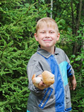 neşeli çocuk bulduğu mantarları gösterir.