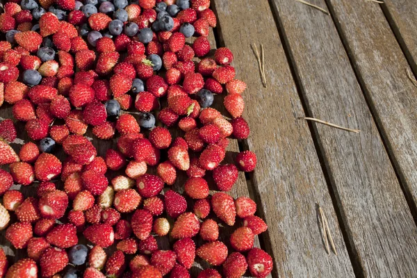 Wilde aardbei en blauwe bosbessen zijn op houten tafel — Stockfoto