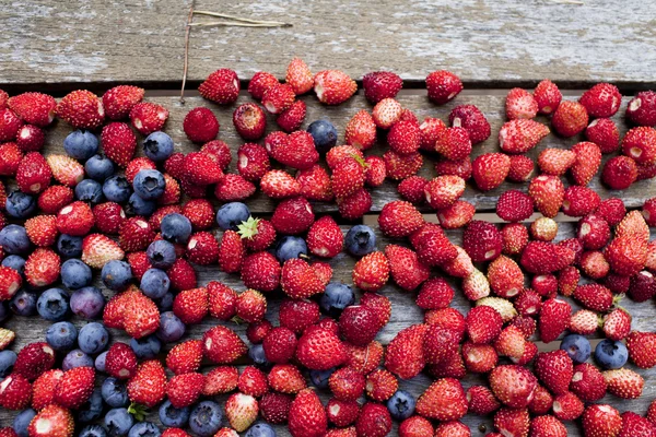 Wilde aardbei en blauwe bosbessen zijn op houten tafel — Stockfoto