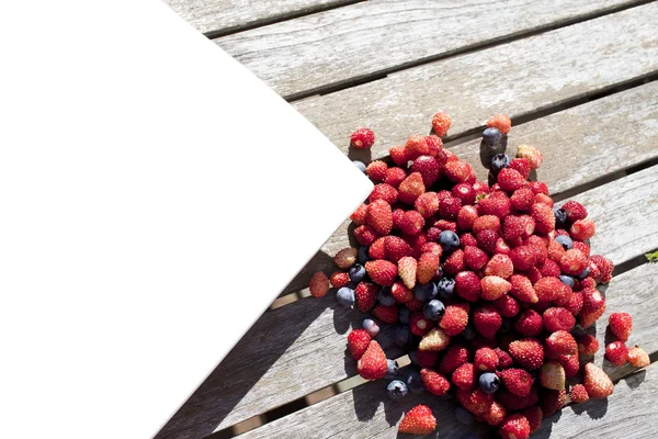 Wild strawberry and bilberry are on the wooden table — Stock Photo, Image