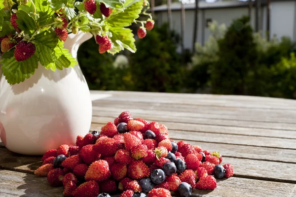 Wilde aardbei en blauwe bosbessen zijn op houten tafel — Stockfoto