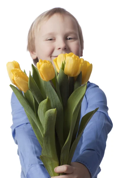 Z ostrości uśmiechnięty chłopiec z żółtych tulipanów — Zdjęcie stockowe