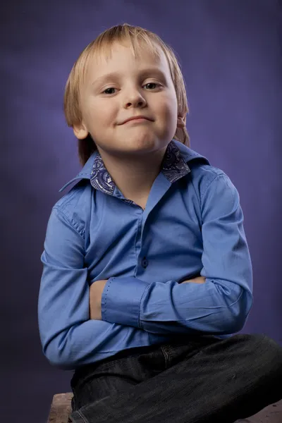 Niño en una camisa azul y pantalones negros sobre fondo púrpura — Foto de Stock